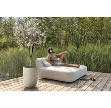 Szene im Freien mit blühendem Baum im Pflanzgefäß und Mann auf einer Liege mit Kissen