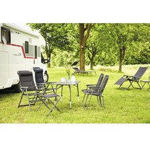 Scène de camping avec caravane, table de camping, chaises de camping et chaises longues sur une pelouse