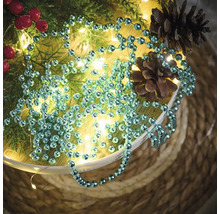 Décoration avec guirlande de boules, branches de sapin, baies rouges, guirlande lumineuse et pommes de pin dans un bol