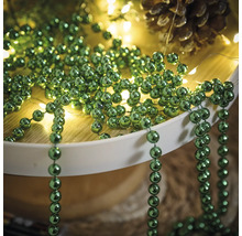 Décoration avec des colliers de perles vertes, une guirlande lumineuse et une pomme de pin