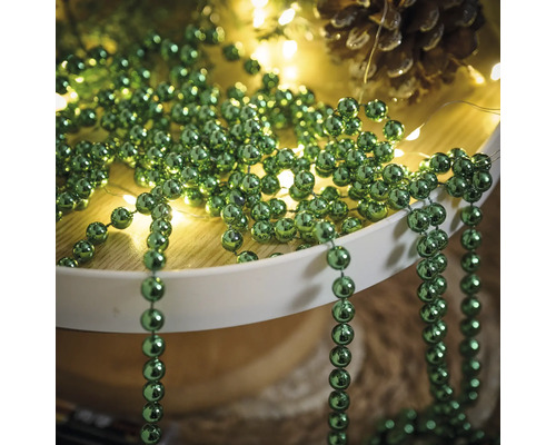 Décoration avec des colliers de perles vertes, une guirlande lumineuse et une pomme de pin