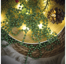 Décoration avec des branches de sapin, une guirlande lumineuse, des pommes de pin et une guirlande de boules vertes