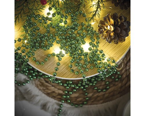 Décoration avec des branches de sapin, une guirlande lumineuse, des pommes de pin et une guirlande de boules vertes