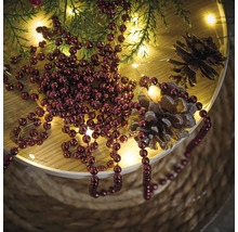Décoration avec boules de Noël, branches de sapin, guirlande lumineuse et pommes de pin sur une table