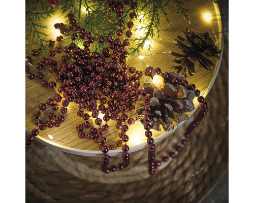 Décoration avec boules de Noël, branches de sapin, guirlande lumineuse et pommes de pin sur une table
