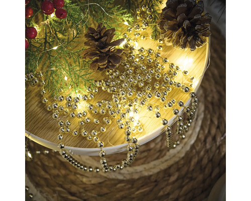 Décoration avec des branches de sapin, des pommes de pin et une guirlande de boules dorées