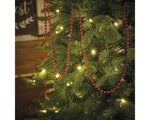 Sapin de Noël décoré avec une guirlande de perles rouges et des illuminations
