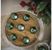 Dekorative grüne Weihnachtskugeln auf einem Holzteller