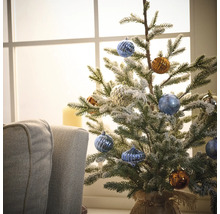 Dekorierter kleiner Weihnachtsbaum mit Christbaumkugeln vor einem Fenster