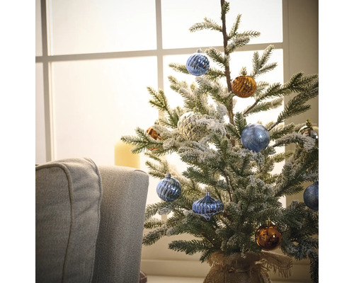 Dekorierter kleiner Weihnachtsbaum mit Christbaumkugeln vor einem Fenster