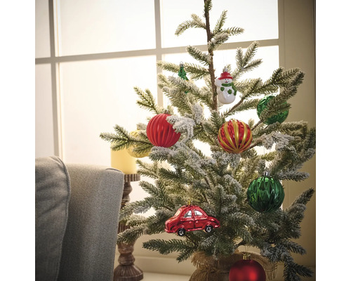 Dekorierter Weihnachtsbaum mit Christbaumkugeln und Autoschmuck vor einem Fenster