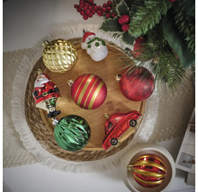 Verschiedene Christbaumkugeln und Dekorationen auf einem runden Holztablett