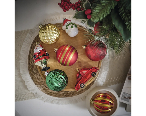 Verschiedene Christbaumkugeln und Dekorationen auf einem runden Holztablett