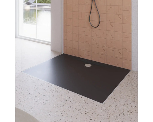 Receveur de douche noir dans une salle de bains avec mur carrelé et douche.