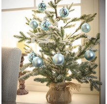 Petit sapin de Noël décoratif avec boules de Noël dans un sac de jute sur un rebord de fenêtre
