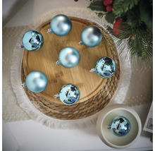 Scène décorative avec des boules de Noël bleues sur une assiette en bois et un dessous de plat tressé