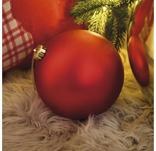 Boule de Noël rouge sur un tapis sous un arbre de Noël