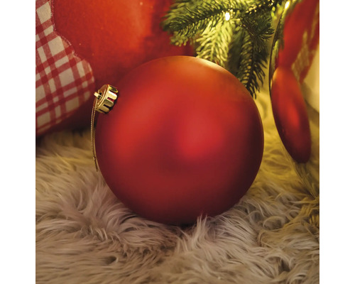 Boule de Noël rouge sur un tapis sous un arbre de Noël