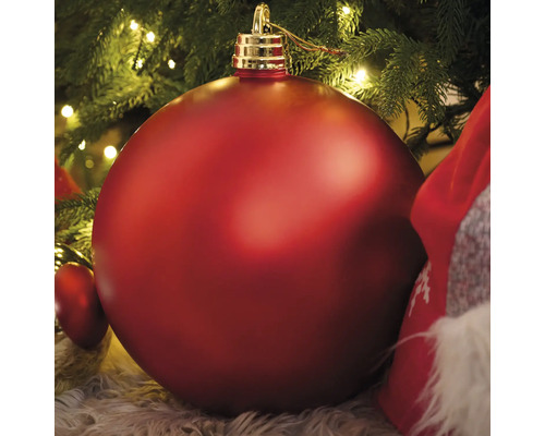 Grande boule de Noël rouge sous un sapin de Noël