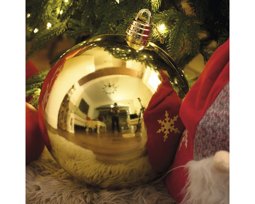 Boule de Noël dorée avec suspension devant un sapin de Noël