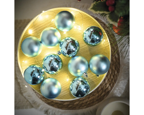Dekorative blaue Christbaumkugeln auf einem Tablett mit Lichterkette