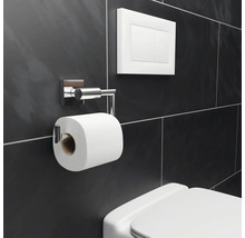 Salle de bains avec porte-papier toilette, plaque de commande et toilettes