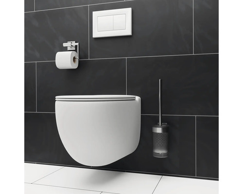 Hänge-WC mit Spülkastenbetätigung, Toilettenpapierhalter und Toilettenbürste an einer Wand mit Fliesen