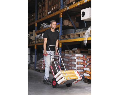 Un homme transporte des sacs à l''aide d''une diable dans un entrepôt.