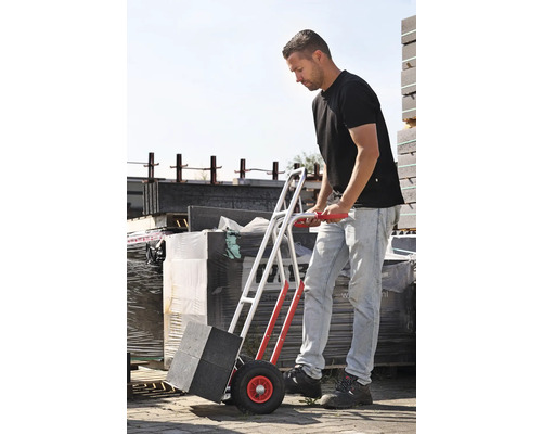 Un homme transporte des pavés avec un diable.