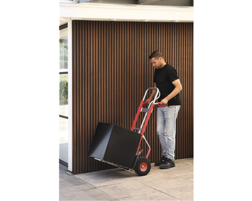 Une personne transporte un carton avec un diable.