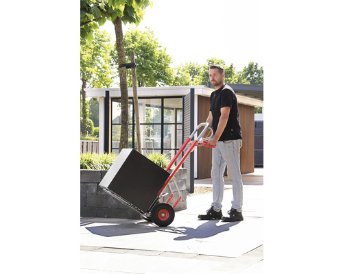 Un homme transporte un paquet noir à l''extérieur à l''aide d''un diable.