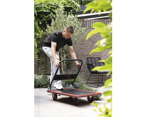Un homme utilise un chariot de transport dans le jardin.
