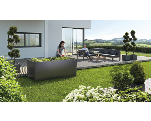 Gartenszene mit Frau beim Bepflanzen eines Hochbeets, einer Sitzecke und dekorativen Pflanzenkübeln auf einer Terrasse.