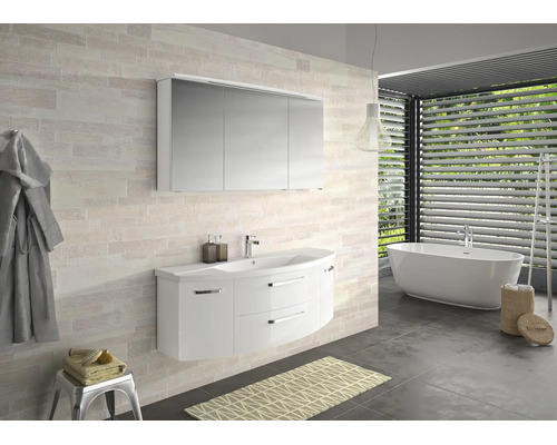 Helles Bad mit weissem Waschtischunterschrank, dreitürigem Spiegelschrank und freistehender Wanne vor hellen Wandfliesen in Steinoptik.