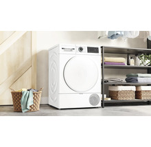 Scène avec un sèche-linge, une étagère et un panier à linge dans une buanderie.