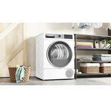 Sèche-linge Bosch autoportant dans une pièce lumineuse à côté d''une étagère et d''un panier à linge.