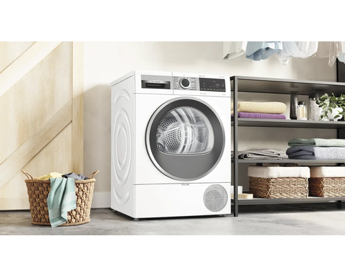 Sèche-linge Bosch autoportant dans une pièce lumineuse à côté d''une étagère et d''un panier à linge.