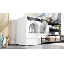Sèche-linge blanc avec porte ouverte dans une buanderie.