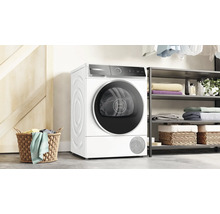 Sèche-linge à pompe à chaleur Bosch blanc, posé à côté d''une étagère et d''un panier à linge.