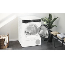 Sèche-linge à pompe à chaleur Siemens autoportant avec porte ouverte dans une pièce lumineuse.