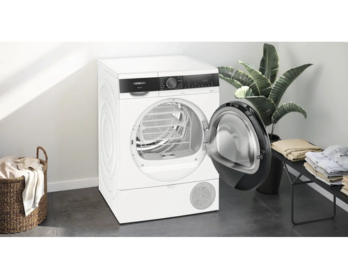 Freistehender Siemens Wärmepumpentrockner mit offener Tür in einem hellen Raum.