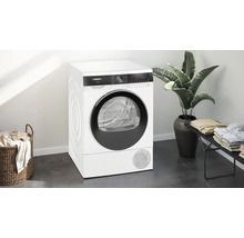 Sèche-linge Siemens dans une pièce lumineuse avec panier à linge et plante d''intérieur