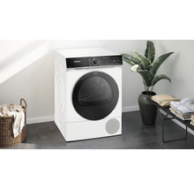 Sèche-linge Siemens dans une pièce lumineuse avec un panier à linge et une plante d''intérieur.