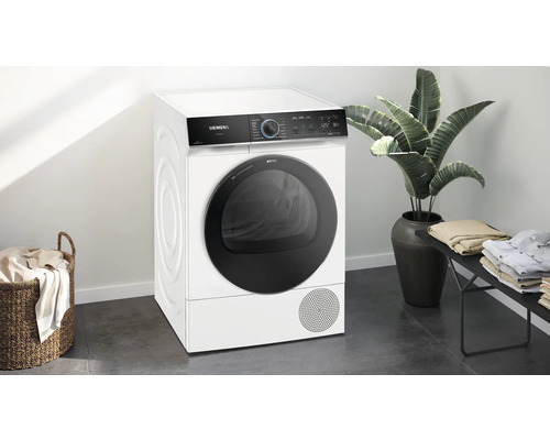 Siemens Trockner in einem hellen Raum mit Wäschekorb und Zimmerpflanze.