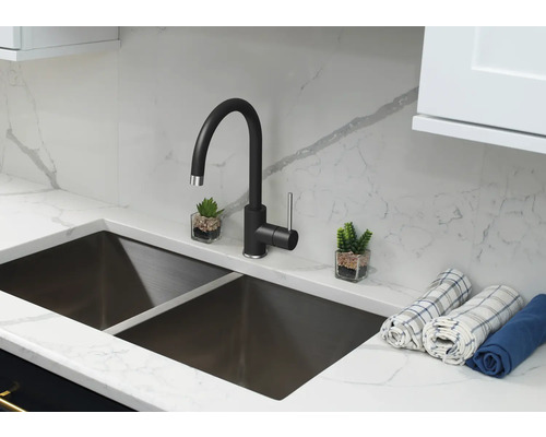 Küchenspüle mit schwarzem Wasserhahn, Arbeitsplatte und zwei kleinen Dekorationen