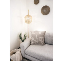 Scène d''intérieur lumineuse avec canapé, coussin à motifs géométriques et lampadaire