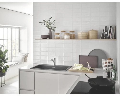 Cuisine claire avec évier, robinet, carreaux muraux et ustensiles de cuisine.