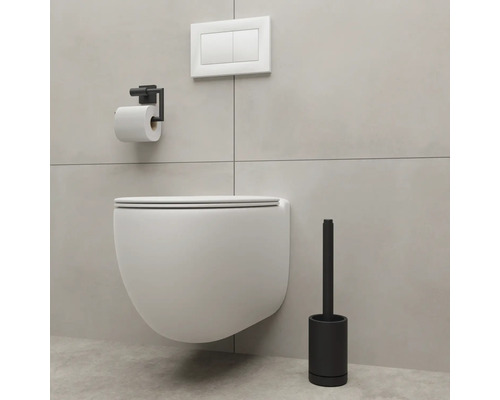 Wandhängendes WC mit Toilettenpapierhalter und Toilettenbürste in einem Badezimmer.