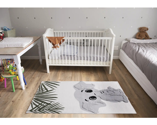Kinderzimmer mit Kinderbett, Wickeltisch, Bett und Teppich mit Elefantenmotiv.