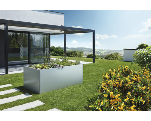 Jardinière surélevée en métal dans un jardin avec des plantes et une terrasse attenante